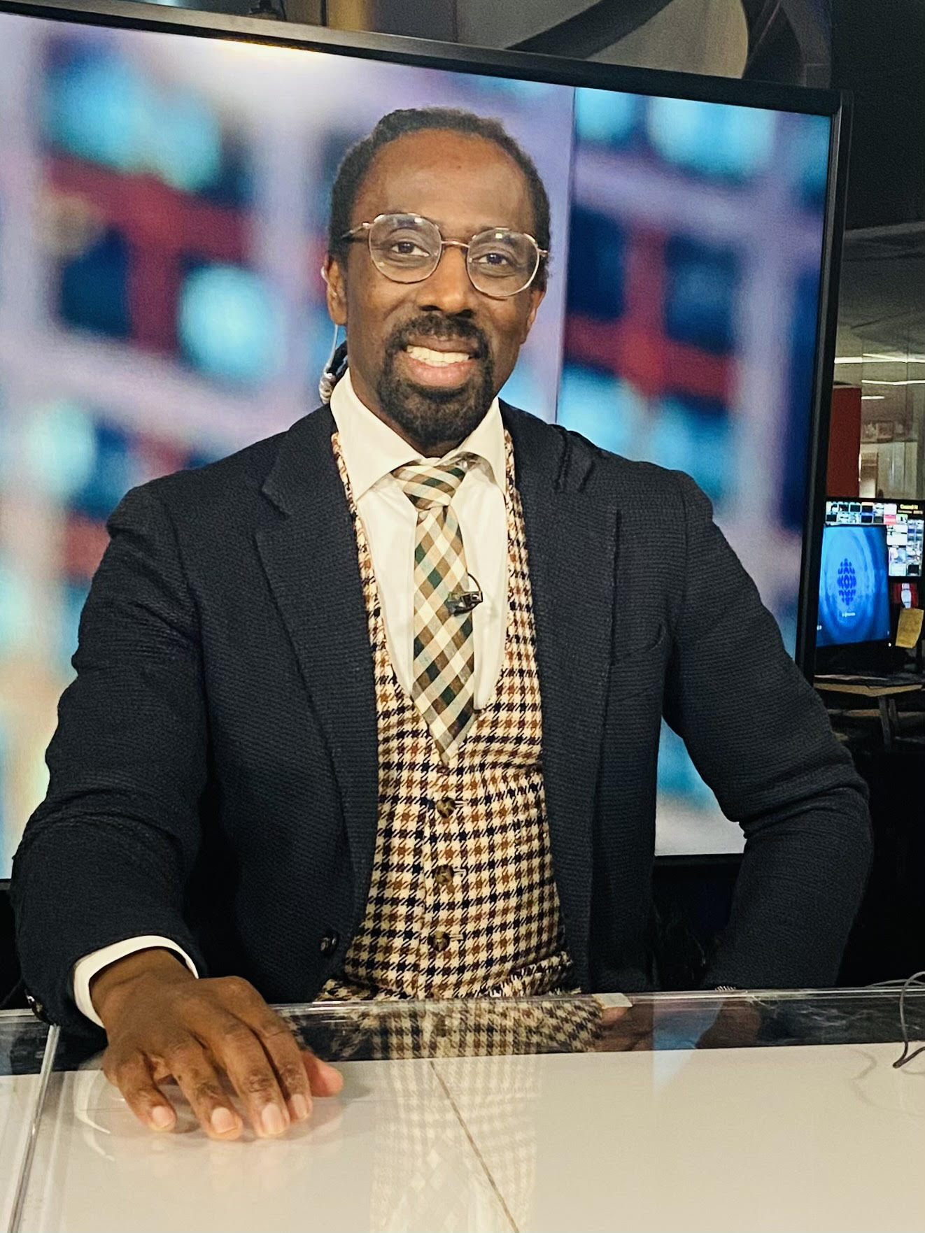 A person with glasses, wearing a white coat and a stethoscope around their neck, smiles at the camera.